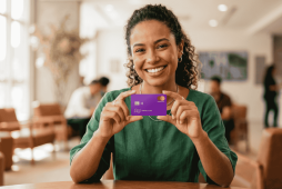 mulher sorrindo e segurando um cartão com NuLimite Garantido