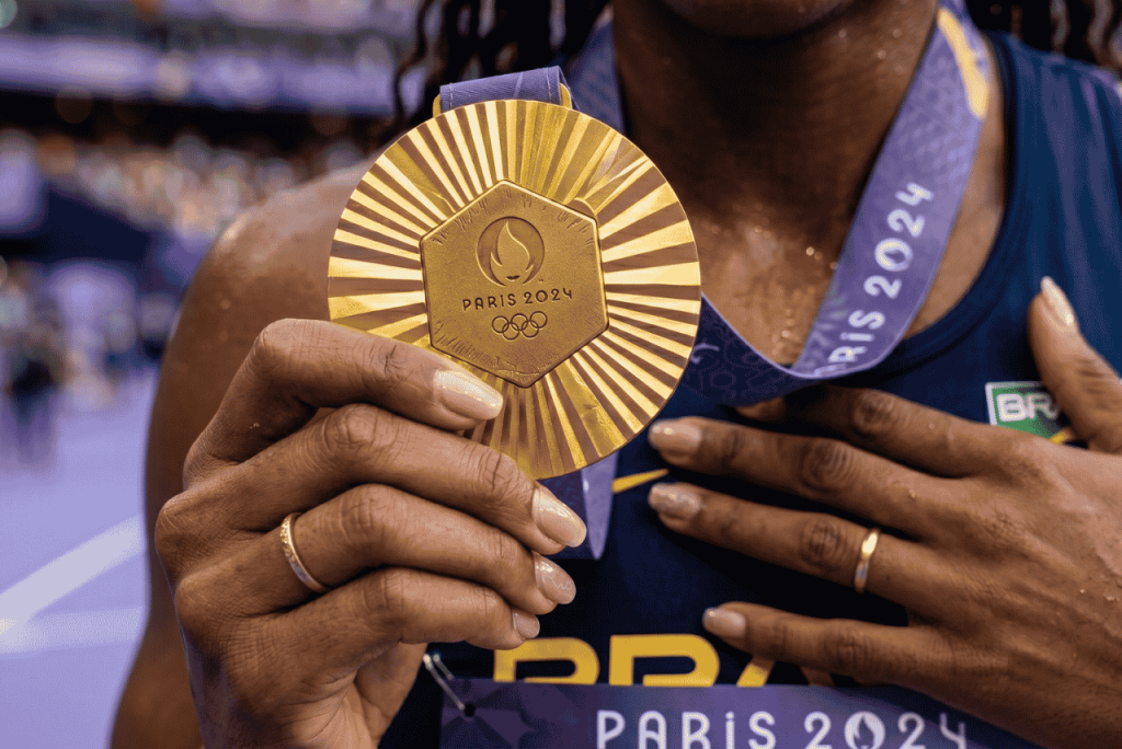 uma mulher segurando uma medalha das olimpíadas para representar Quanto ganha um medalhista olímpico